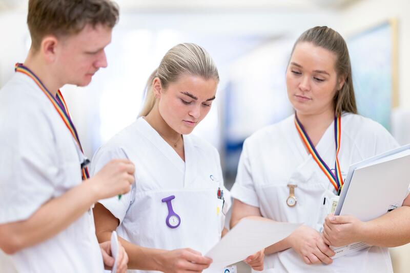 Tre sykepleiere ser ned på et ark